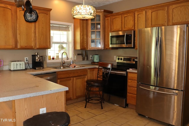 kitchen featuring pendant lighting, sink, light tile patterned floors, appliances with stainless steel finishes, and kitchen peninsula