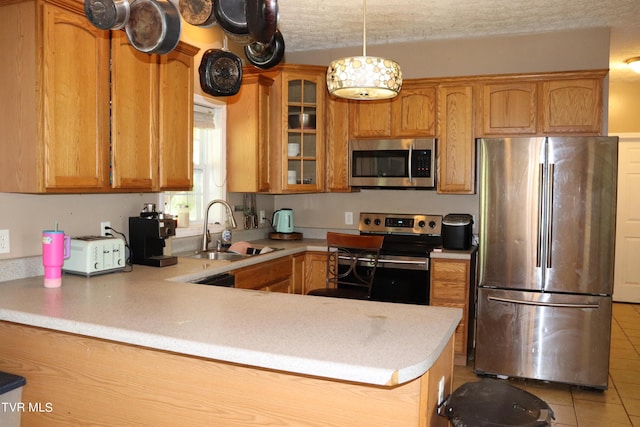 kitchen with sink, a textured ceiling, appliances with stainless steel finishes, kitchen peninsula, and pendant lighting