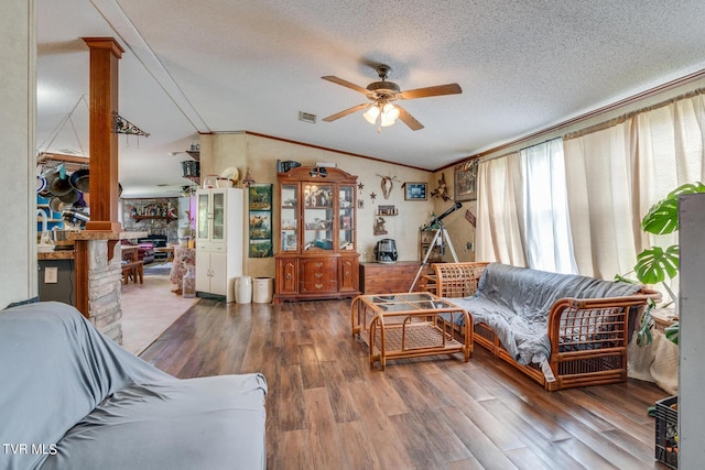 living room featuring lofted ceiling, ceiling fan, wood-type flooring, ornamental molding, and a textured ceiling