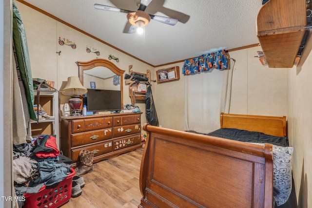 bedroom featuring light hardwood / wood-style flooring, ceiling fan, ornamental molding, a textured ceiling, and vaulted ceiling