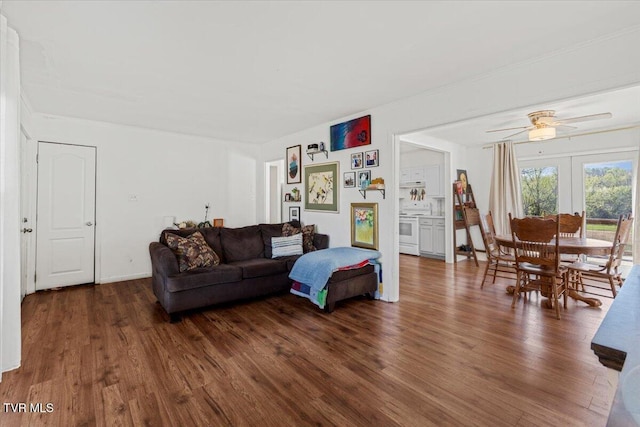 living area with crown molding, a ceiling fan, and wood finished floors