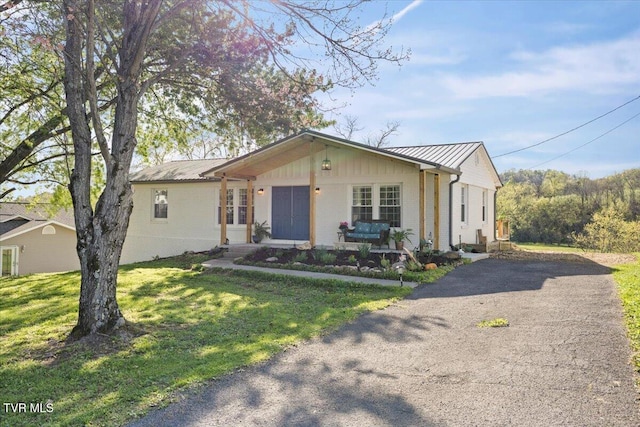 single story home with metal roof, a front yard, and aphalt driveway