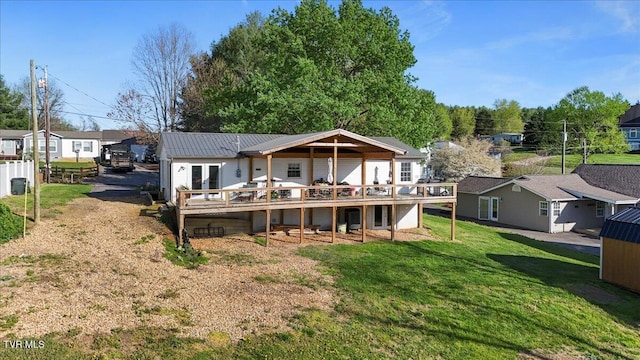 back of house featuring a yard, a deck, metal roof, and a standing seam roof
