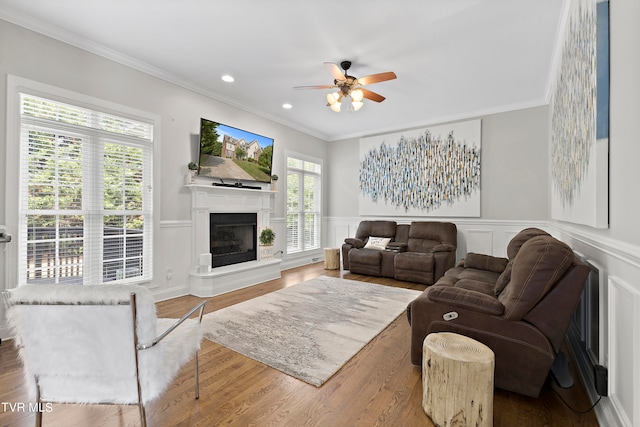 living room with crown molding, wood-type flooring, and ceiling fan