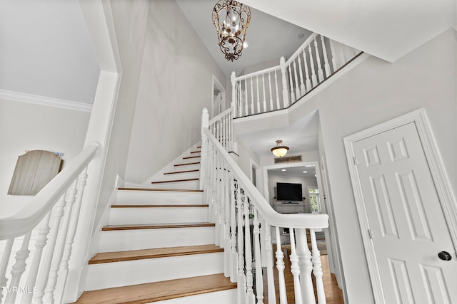 stairway featuring hardwood / wood-style floors, an inviting chandelier, and a high ceiling