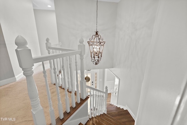 stairs with hardwood / wood-style floors, an inviting chandelier, and a towering ceiling