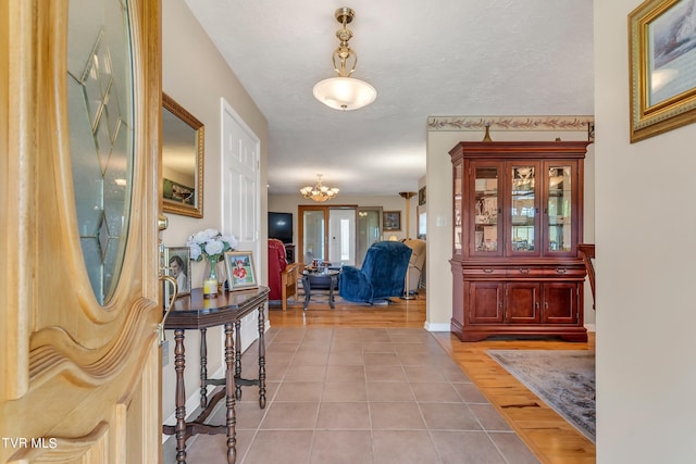 entrance foyer featuring a textured ceiling, a chandelier, and light hardwood / wood-style floors