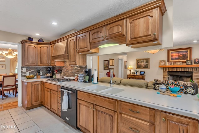 kitchen featuring light tile patterned floors, an inviting chandelier, a brick fireplace, custom exhaust hood, and stainless steel appliances