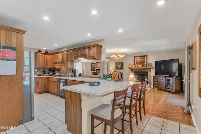 kitchen with light hardwood / wood-style flooring, stainless steel appliances, decorative light fixtures, kitchen peninsula, and a breakfast bar