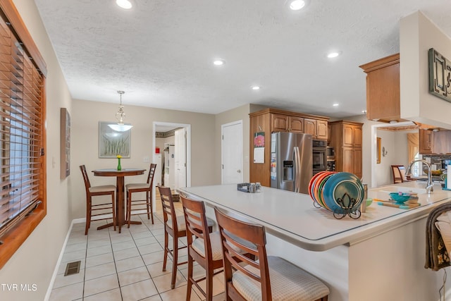 kitchen featuring appliances with stainless steel finishes, sink, kitchen peninsula, a breakfast bar, and a textured ceiling