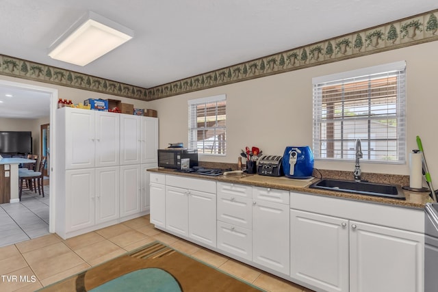 kitchen with dark stone counters, light tile patterned floors, sink, and white cabinets