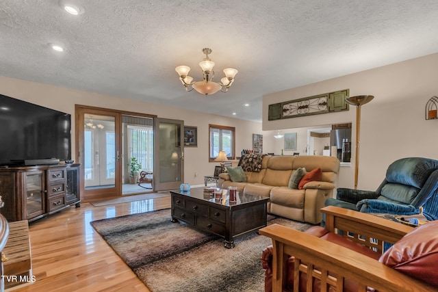 living room featuring french doors, a chandelier, a textured ceiling, and light hardwood / wood-style flooring