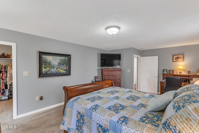 bedroom with carpet flooring, a textured ceiling, a walk in closet, and a closet