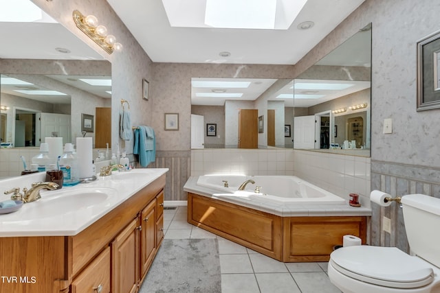 bathroom with toilet, tile patterned flooring, vanity, a skylight, and a bathtub