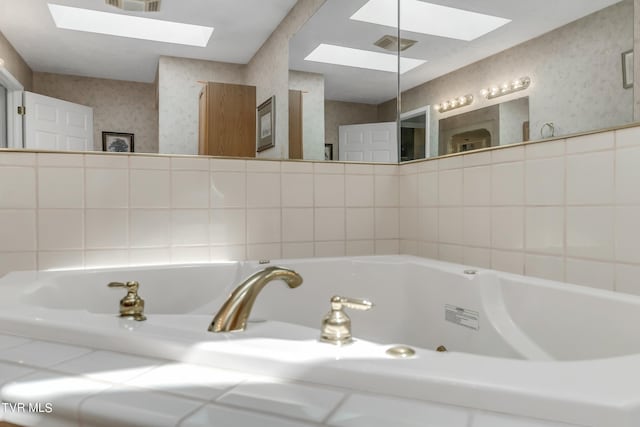 bathroom featuring a skylight and a tub to relax in