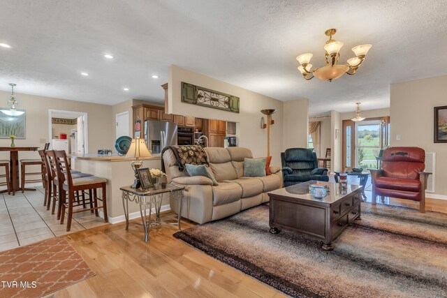 living room featuring a chandelier, a textured ceiling, and light hardwood / wood-style flooring