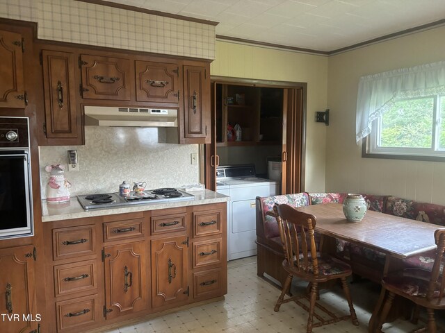 kitchen with crown molding, washer and clothes dryer, gas cooktop, ventilation hood, and oven