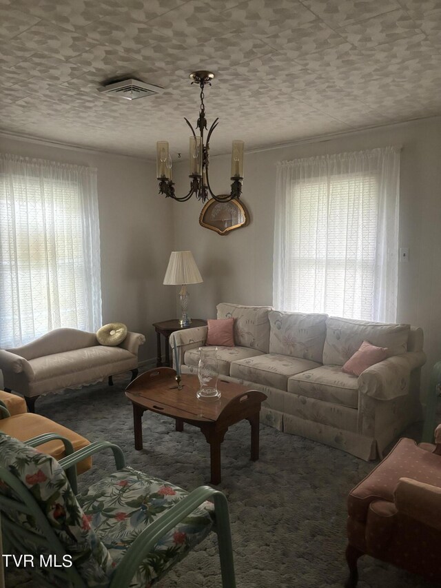 living room featuring plenty of natural light, carpet, and an inviting chandelier