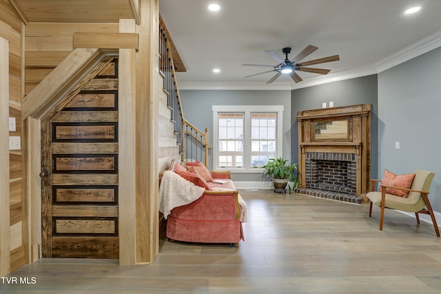 sitting room featuring crown molding, ceiling fan, light hardwood / wood-style floors, and a brick fireplace