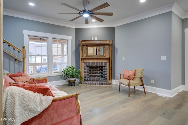 living room featuring light hardwood / wood-style floors, ornamental molding, and a brick fireplace