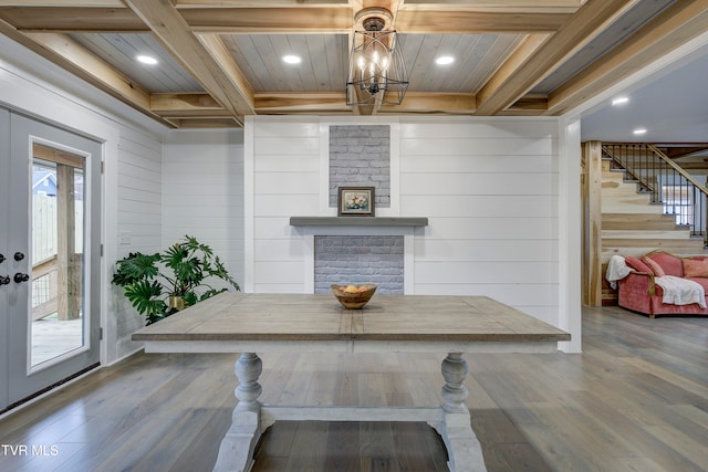 dining space with wood walls, an inviting chandelier, beamed ceiling, wood-type flooring, and wood ceiling