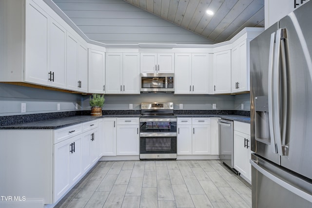 kitchen with wooden ceiling, dark stone counters, white cabinets, vaulted ceiling, and appliances with stainless steel finishes