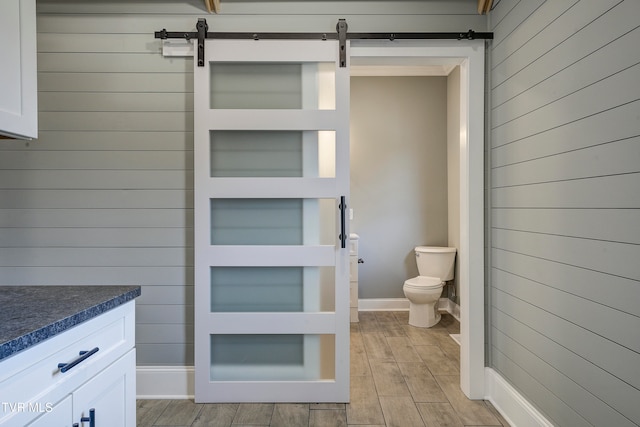 bathroom with vanity, wood walls, toilet, and wood-type flooring