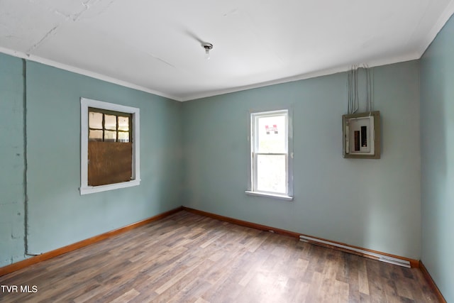 spare room featuring wood-type flooring, electric panel, and ornamental molding