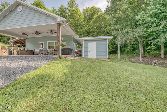 view of front of property featuring a patio area, an outdoor structure, ceiling fan, a front lawn, and an outdoor living space