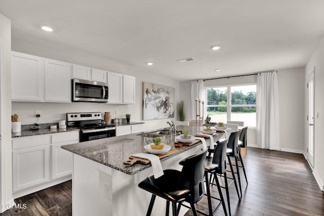 kitchen with appliances with stainless steel finishes, sink, white cabinets, and a center island with sink