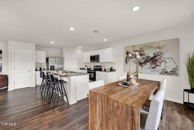 kitchen with a kitchen breakfast bar, stainless steel appliances, white cabinets, a center island, and sink