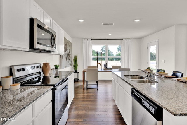 kitchen with an island with sink, light stone countertops, sink, appliances with stainless steel finishes, and white cabinets