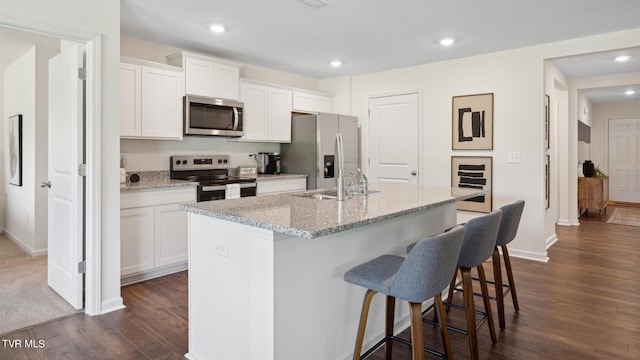 kitchen with white cabinetry, stainless steel appliances, and an island with sink