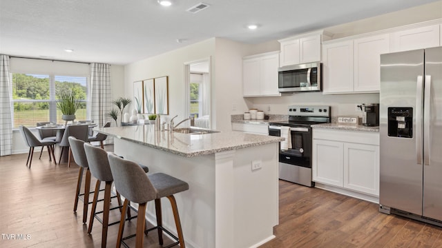 kitchen with sink, white cabinetry, stainless steel appliances, dark hardwood / wood-style floors, and an island with sink