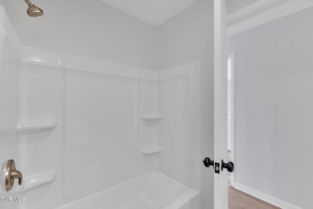 bathroom with bathing tub / shower combination and hardwood / wood-style flooring