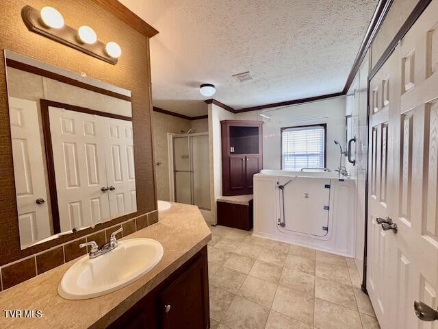 bathroom featuring tile patterned floors, a textured ceiling, a shower with door, vanity, and ornamental molding