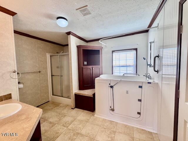 bathroom with a textured ceiling, crown molding, vanity, and an enclosed shower