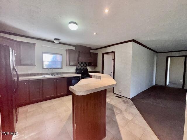 kitchen featuring crown molding, sink, wall chimney range hood, a kitchen island, and stainless steel refrigerator