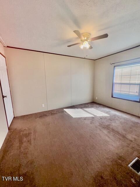 carpeted spare room featuring ceiling fan and a textured ceiling