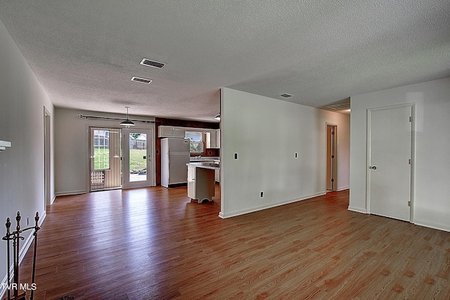 unfurnished living room with light hardwood / wood-style floors and a textured ceiling