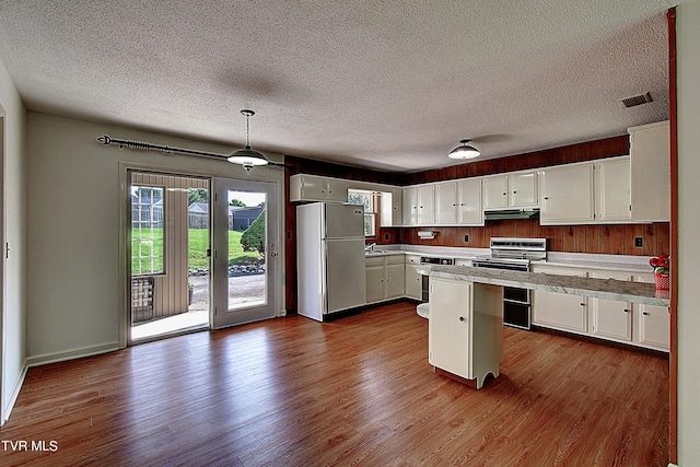 kitchen featuring electric stove, refrigerator, hanging light fixtures, and white cabinets