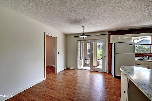 unfurnished dining area with sink, light hardwood / wood-style floors, and a textured ceiling