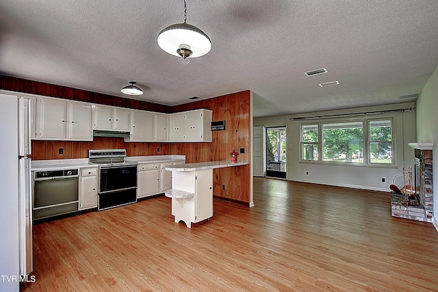 kitchen with electric range oven, a breakfast bar area, white cabinets, white refrigerator, and a center island