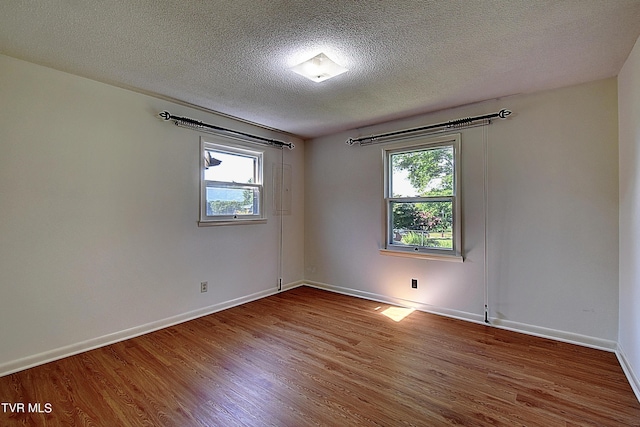 unfurnished room with hardwood / wood-style flooring, plenty of natural light, and a textured ceiling