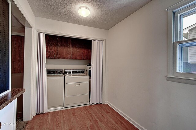 washroom featuring cabinets, separate washer and dryer, a textured ceiling, and light hardwood / wood-style floors