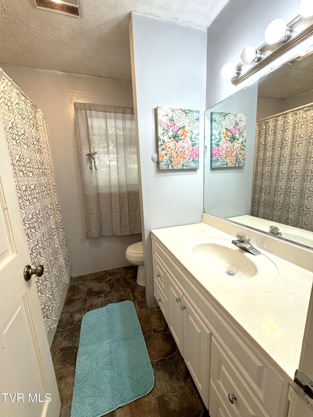 bathroom featuring vanity, a textured ceiling, and toilet