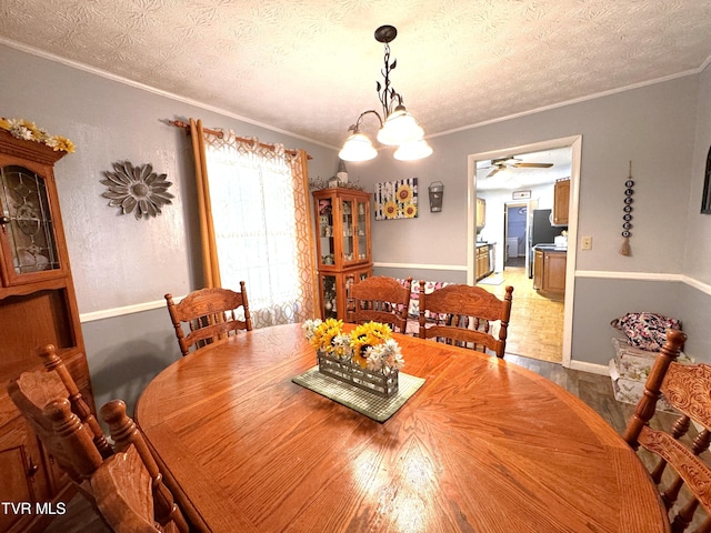 dining space with crown molding, ceiling fan with notable chandelier, and a textured ceiling