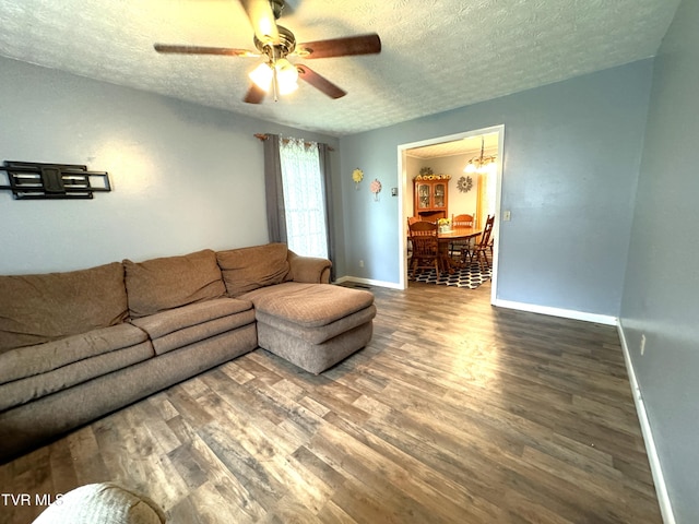 living room featuring ceiling fan, dark wood-type flooring, and a textured ceiling