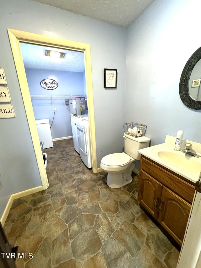 bathroom with vanity, a textured ceiling, independent washer and dryer, and toilet