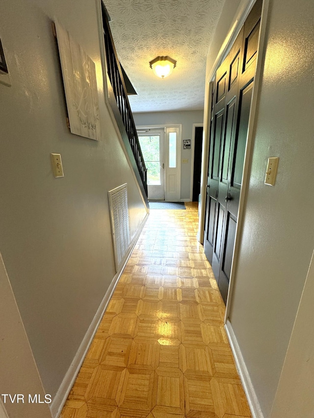 corridor featuring light parquet flooring and a textured ceiling